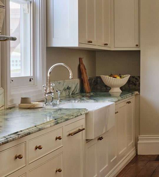 Best brass kitchen tap, traditional bridge tap style with rounded spout and lever handles, over a butler sink.