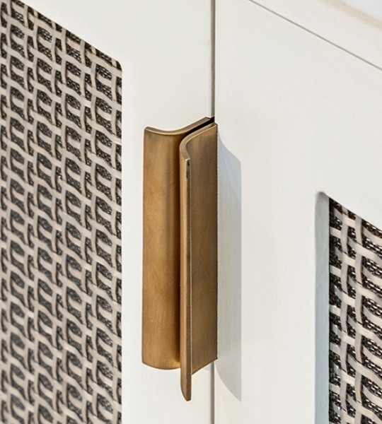 White cabinet front frames inset with best woven metal decorative grilles in basketweave pattern with mesh backing.