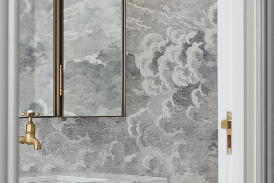 Cloud patterned wallpaper provides interesting backdrop to vintage style wash house pillar taps in contemporary bathroom.
