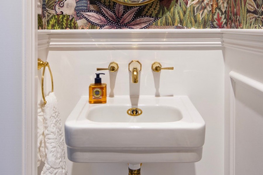 Polished brass Art Deco bathroom taps with octagonal facet detail over traditional wash hand basin in powder room.
