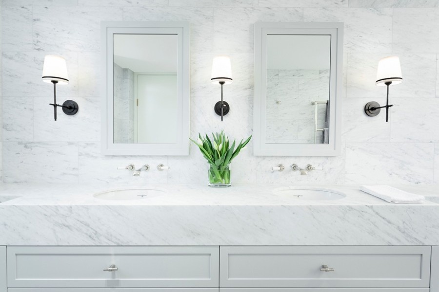 Chrome finish t-bar handles and traditional basin wall-mounted taps glisten in marble lined ensuite bathroom.