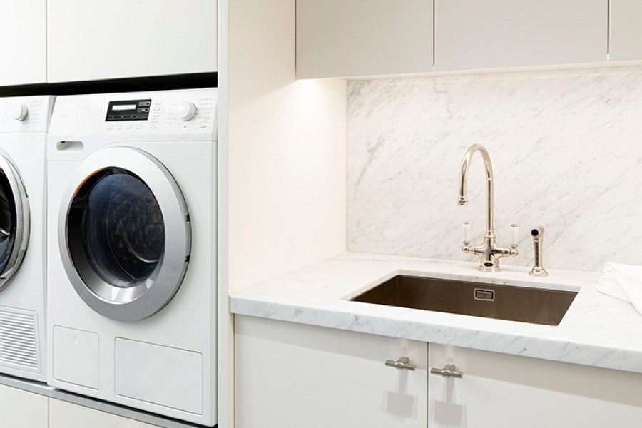 Nickel plated laundry taps and nickel t-bar cabinet handles adorn a luxury apartment laundry.

