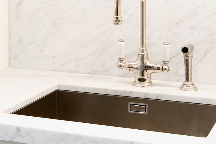 Close up of kitchen tap and cabinet handles in matching nickel finish are quality fittings in this luxury apartment laundry.
