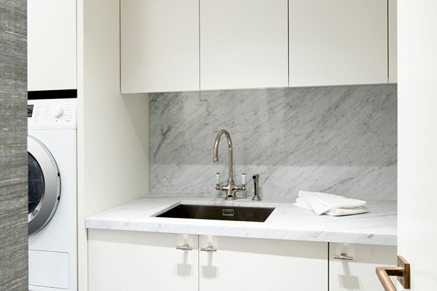 Stainless steel laundry sink and traditional kitchen tap with round spout and twin white ceramic levers in contemporary laundry.
