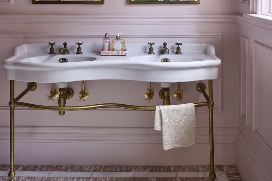 In the master ensuite, The Water Monopoly Paris Double Vanity takes centre stage with its sculptural ceramic form, elegantly raised on brass legs and set against a soft pink backdrop.