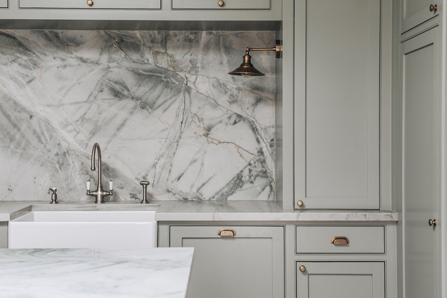 Quartzite backsplash provides stunning backdrop to traditional kitchen tap in pewter finish with white porcelain handles.
