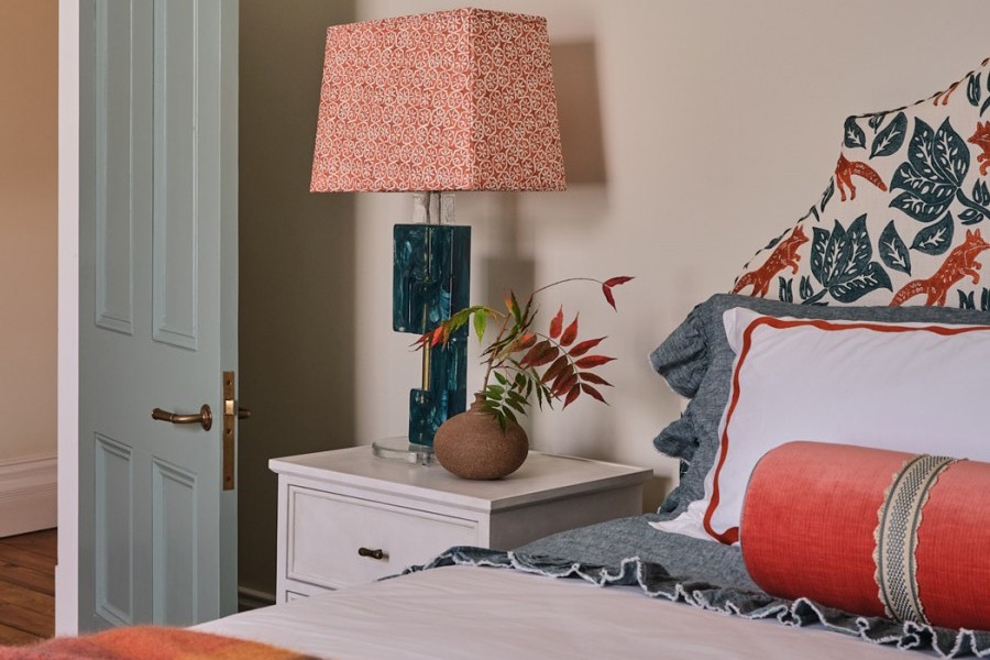 Kids’ bedroom with blue and orange accents that coordinate with the adjoining bathroom, featuring a bed and playful decor.

