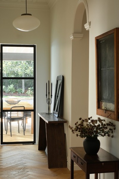 Ralph Hotere black window painting adorns cream wall in high ceiling villa with parquet flooring.

