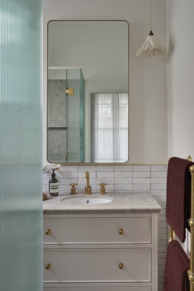 Raw brass towel warmer, brass cabinet knobs and traditional brass basin taps take focus in designer ensuite.
