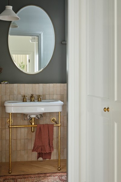 Traditional basin on natural brass basin stand with brass bathroom taps and exposed pipework displaying aging patina.