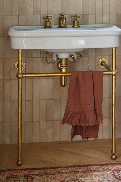 White basin on brass basin stand with matching brass pillar taps with crosshead handles creates a traditional powder room.
