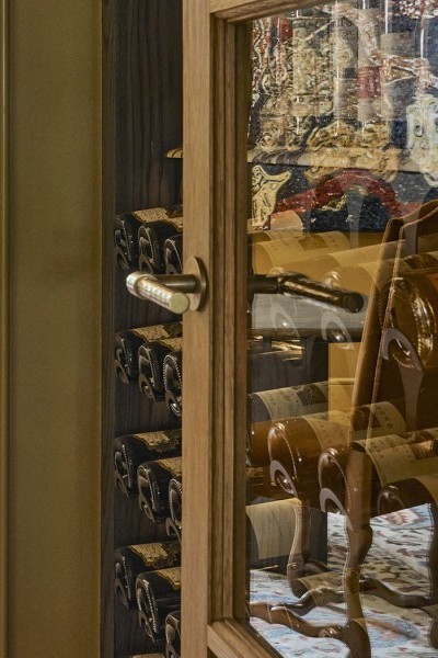 A door with a Joseph Giles hammered brass oval doorknob from The English Tapware Company opens into a wine cupboard. 