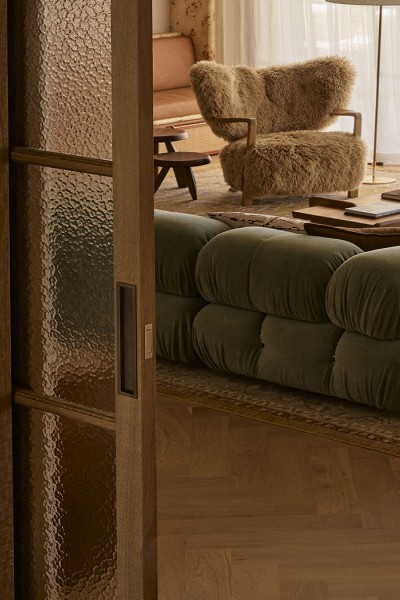 A sliding timber and glass door with Joseph Giles rectangular solid brass recessed pull, opens into a cosy living room.