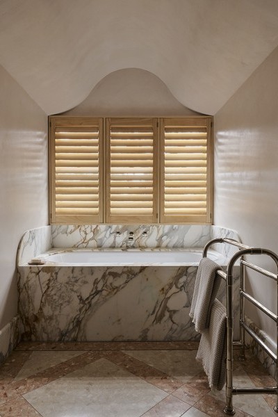 A classic nickel towel rack next to a marble bath featuring Perrin & Rowe traditional hot and cold taps and mixer. 