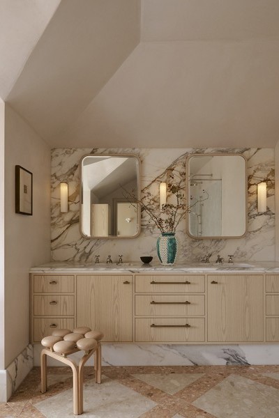 A pink ensuite bathroom with marble features, showcases Perrin & Rowe classic hot and cold taps with a sink mixer. 