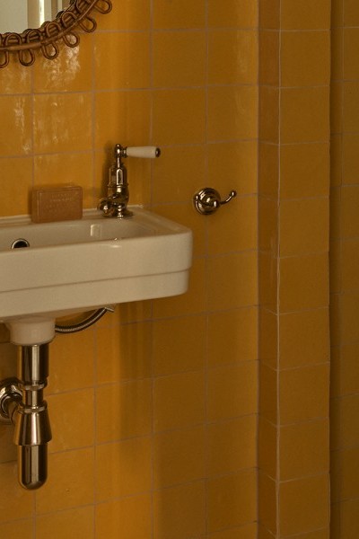 A powder-room with orange square tiles with mini white Deco style Soho basin from The English Tapware Company and Polished Nickel classical Perrin & Rowe pillar taps.