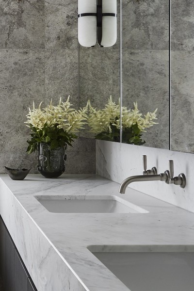 Modern basin mixer with separate hot and cold lever taps and tubular basin spout hovers above slick marble bathroom vanity.
