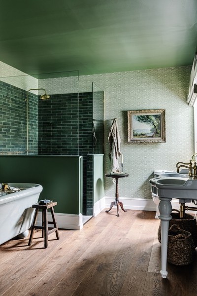 Voluptuously curved twin basin and green bath are complemented by traditional brass tapware and shower taps.
