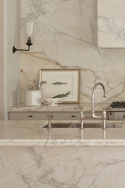 A Perrin & Rowe Ionian Tap two-hole mixer with spray rinse, in polished nickel sits in marble kitchen. 