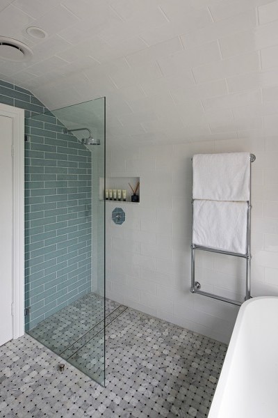 Chrome Art Deco shower mixer with octagonal plate  and traditional chrome wall mounted towel warmer in tiled bathroom.
