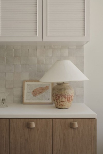 Kitchen joinery in timber with white stone bench top and cabinetry. Texture lamp and fish print on bench top. 