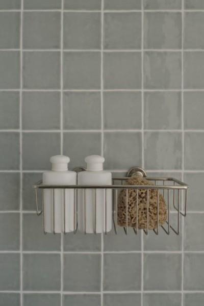 Extra large nickel soap basket on tiled wall with shampoo bottles and sponge