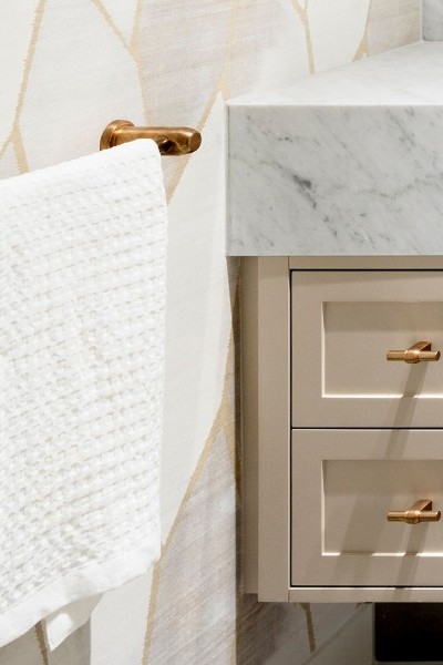 Glamorous bathroom showcases brass bathroom taps, a brass towel rail, and matching t-bar drawer handles.

