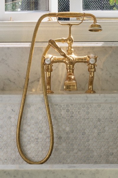 In the laundry, the use of a polished brass Perrin & Rowe bath mixer with hand shower and crosshead taps is cleverly used to introduce a refined sense of luxury to a traditionally utilitarian space. 