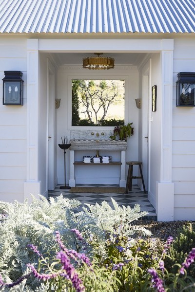 Garden entrance to Steve Cordony's pool house featuring rustic marble trough and aging brass wall-mounted basin tapware.
