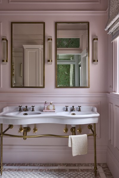 In the master ensuite, The Water Monopoly Paris Double Vanity takes centre stage with its sculptural ceramic form, elegantly raised on brass legs and set against a soft pink backdrop.