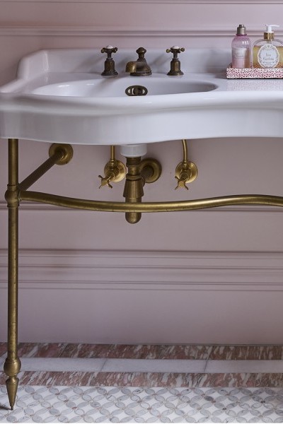 In the master ensuite, The Water Monopoly Paris Double Vanity takes centre stage with its sculptural ceramic form, elegantly raised on brass legs and set against a soft pink backdrop.