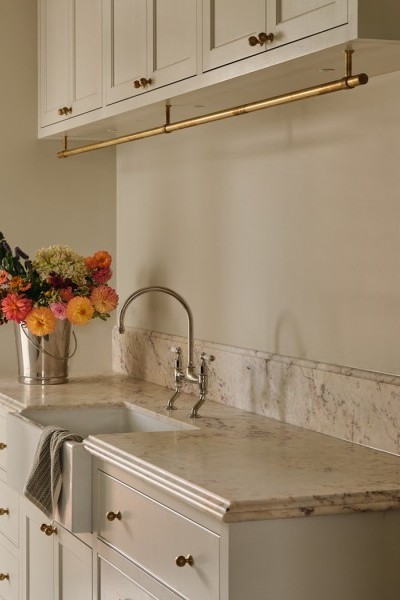 Laundry with soft cream and warm beige tones, Joseph Giles brass hanging rails, Perrin & Rowe tapware, and Armac Martin cabinetry opening toward the garden.