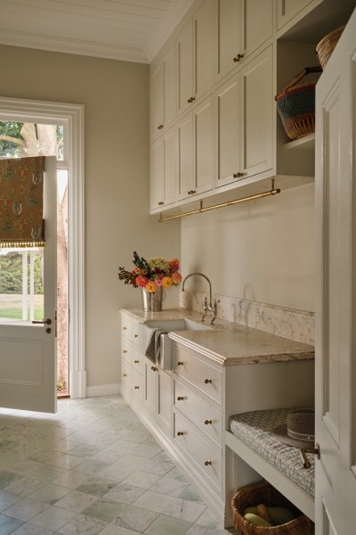 Laundry with soft cream and warm beige tones, Joseph Giles brass hanging rails, Perrin & Rowe tapware, and Armac Martin cabinetry opening toward the garden.