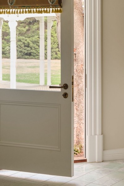 Laundry with soft cream and warm beige tones, Joseph Giles brass hanging rails, Perrin & Rowe tapware, and Armac Martin cabinetry opening toward the garden.