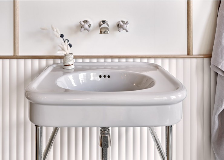 Grey glazed bathroom basin vanity on chrome metal basin stand with matching wall-mounted basin taps with grey crosshead handles.