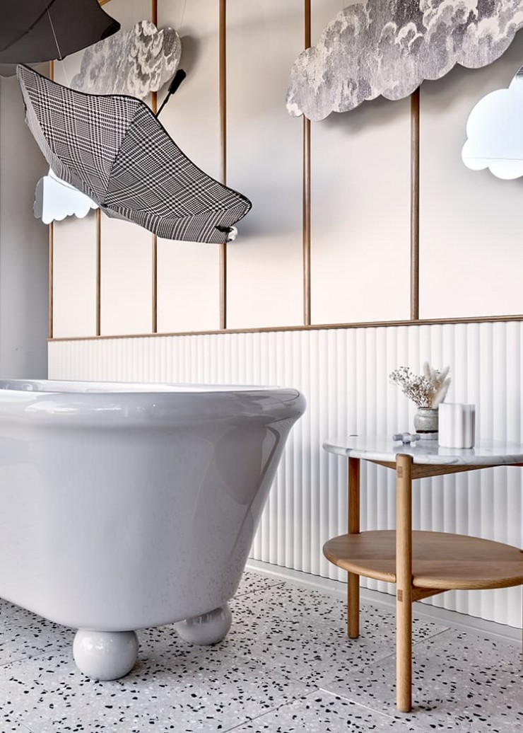 Blunt umbrellas and cut-out clouds complete imaginative bathroom window display featuring grey freestanding bath with feet.