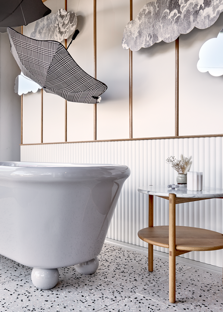 Blunt umbrellas and cut-out clouds complete imaginative bathroom window display featuring grey freestanding bath with feet.